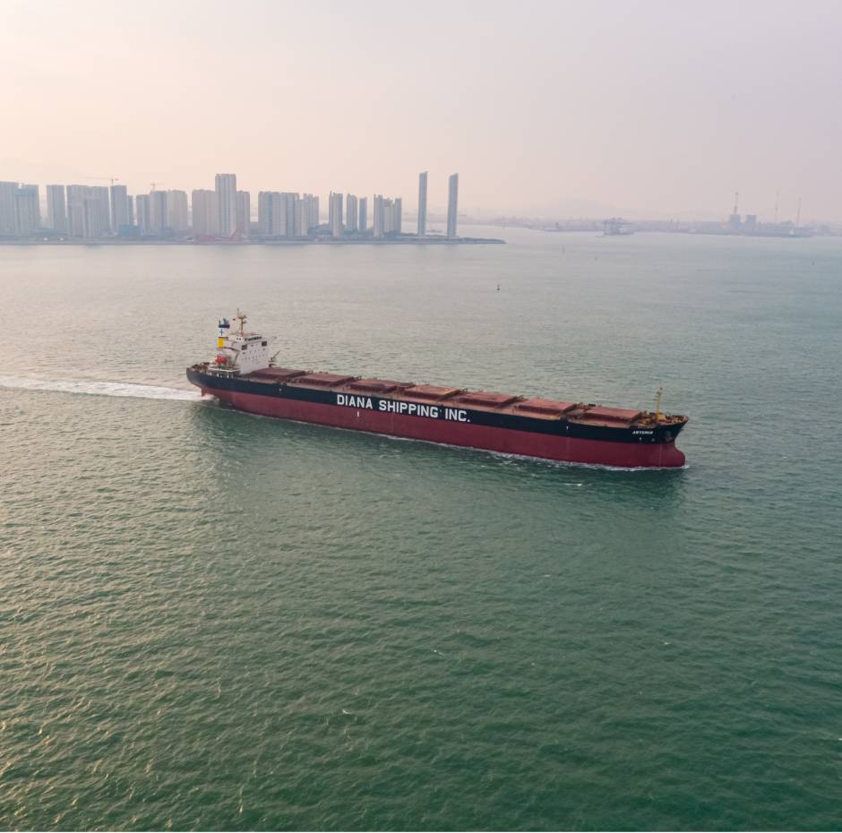 Diana Shipping vessel sails near a coastal cityscape, showcasing maritime logistics